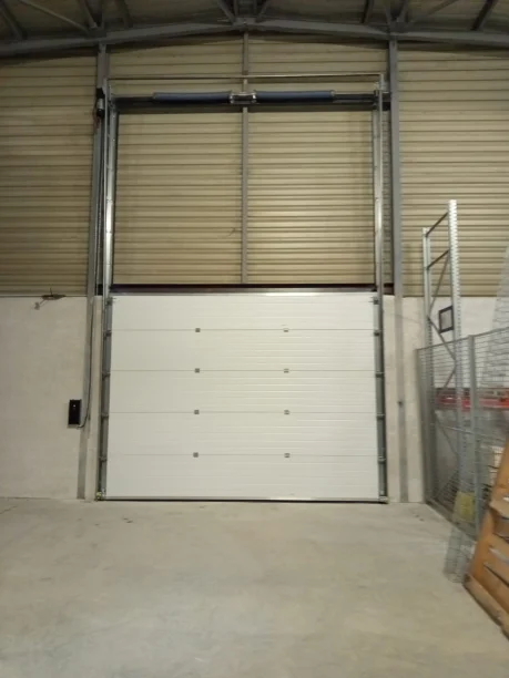 Porte sectionnelle verticale blanche motorisée en aluminium dans bâtiment industriel à Montpellier