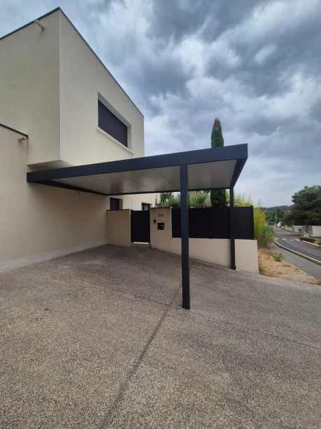 Carport gris anthracite en aluminium adossé avec poteau déporté dans l’Hérault, vue extérieure latérale