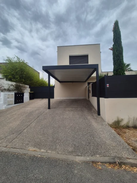 Carport gris anthracite en aluminium adossé avec poteau déporté dans l’Hérault, vue extérieure