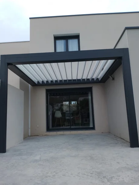 Pergola bioclimatique à toit rétractable grise aluminium Marquises et store projection Hérault vue extérieure