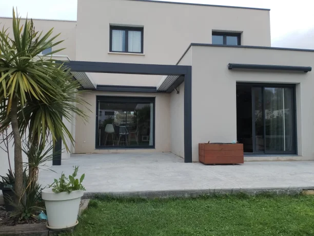 Pergola bioclimatique à toit rétractable grise aluminium Marquises et store projection Hérault vue extérieure latérale